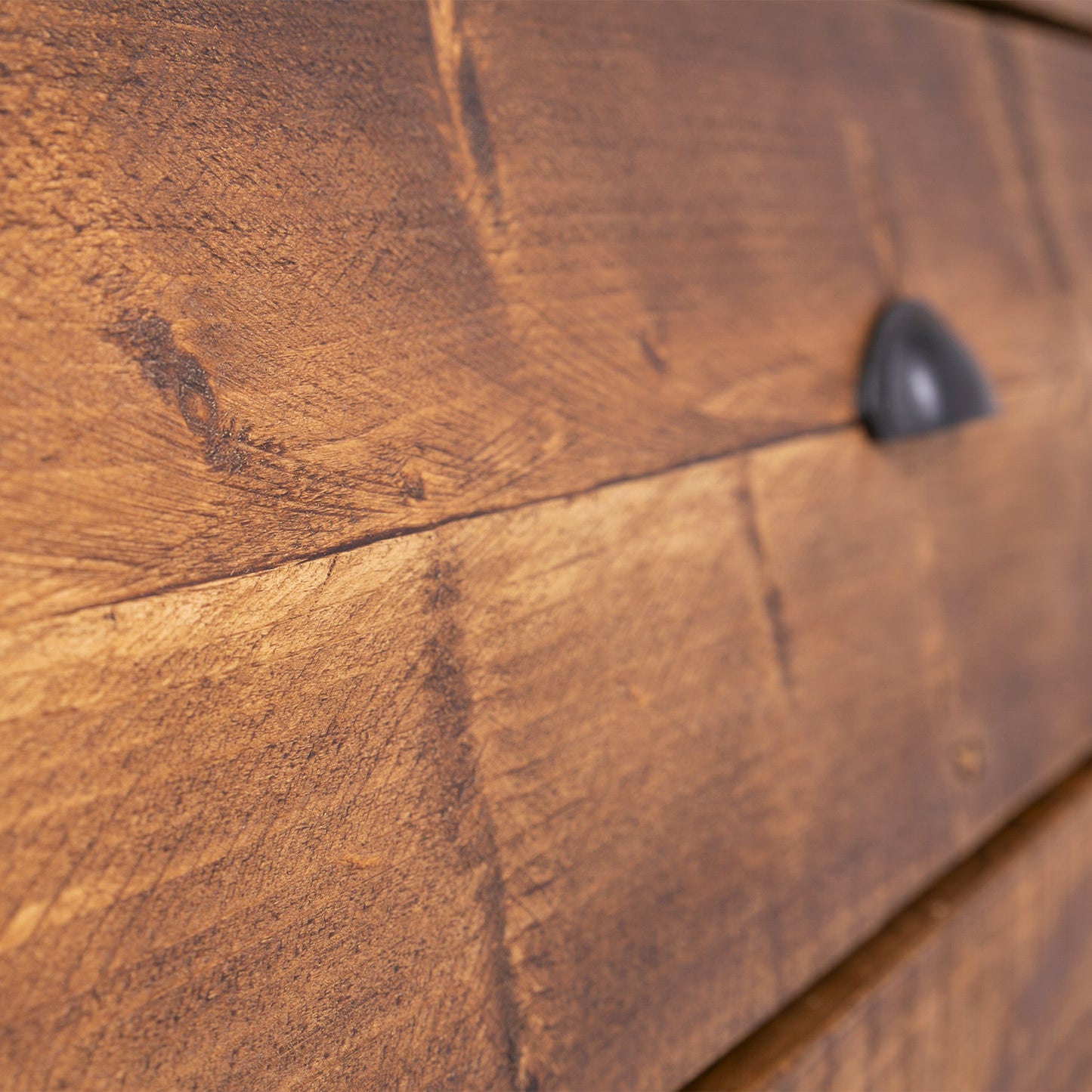 Wooden bedroom drawer set. Close up of wood grain with black handle on show. Rustic waxed finish