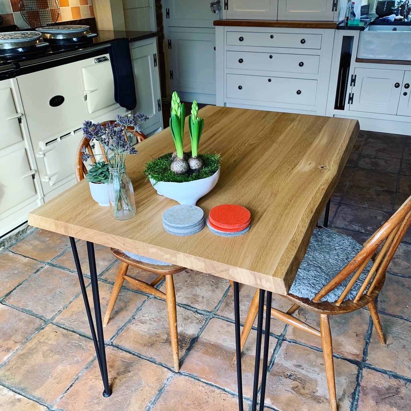 A waney live edge oak dining table with black steel hairpin legs in a beautiful rustic kitchen