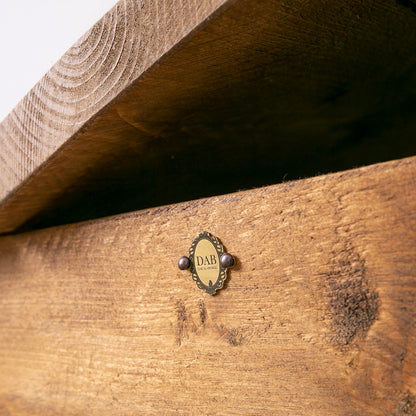 Close up of side of wooden storage trunk with badge on show and lid slightly ajar